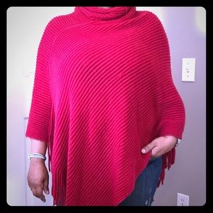 Red turtleneck poncho with fringe.